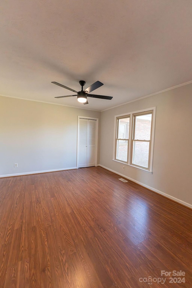 unfurnished bedroom featuring ceiling fan, ornamental molding, and dark wood-type flooring