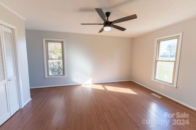 unfurnished bedroom with a closet, hardwood / wood-style flooring, multiple windows, and ceiling fan