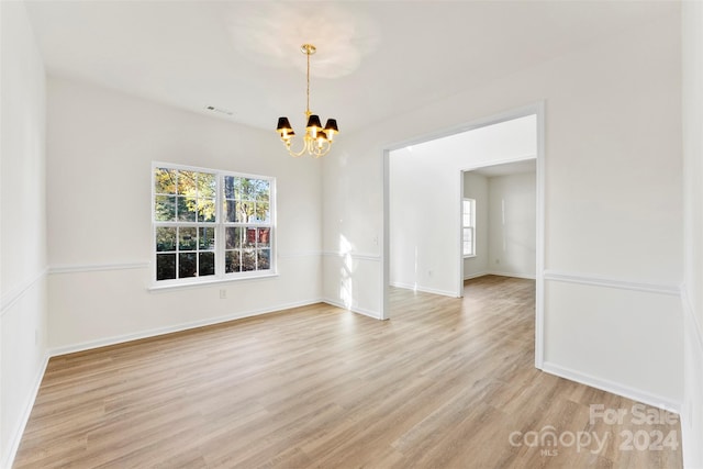 unfurnished dining area featuring light wood-type flooring and an inviting chandelier