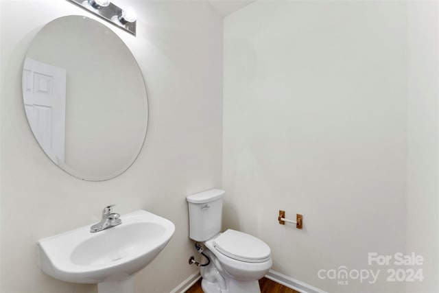 bathroom with wood-type flooring, toilet, and sink