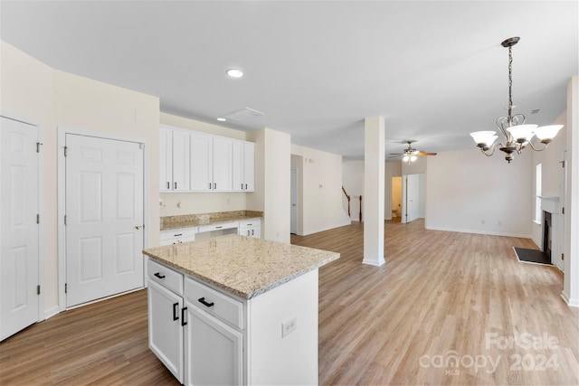 kitchen with white cabinetry, light hardwood / wood-style flooring, ceiling fan with notable chandelier, and decorative light fixtures