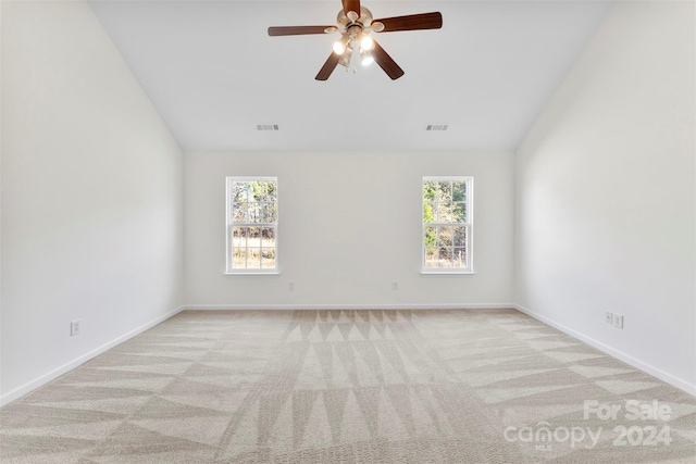 carpeted spare room featuring ceiling fan, a healthy amount of sunlight, and lofted ceiling