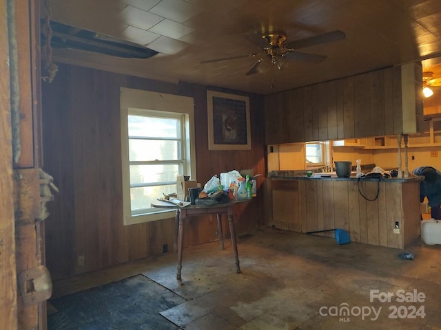 interior space featuring ceiling fan and wood walls