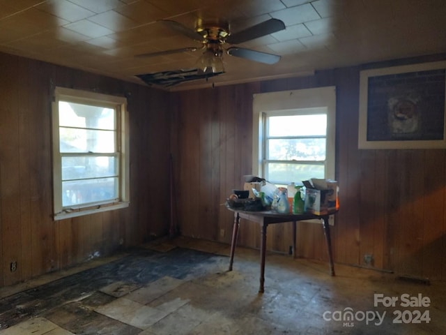 dining area with ceiling fan and wood walls