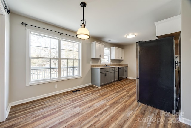 kitchen with gray cabinets, white cabinetry, stainless steel appliances, and light hardwood / wood-style flooring