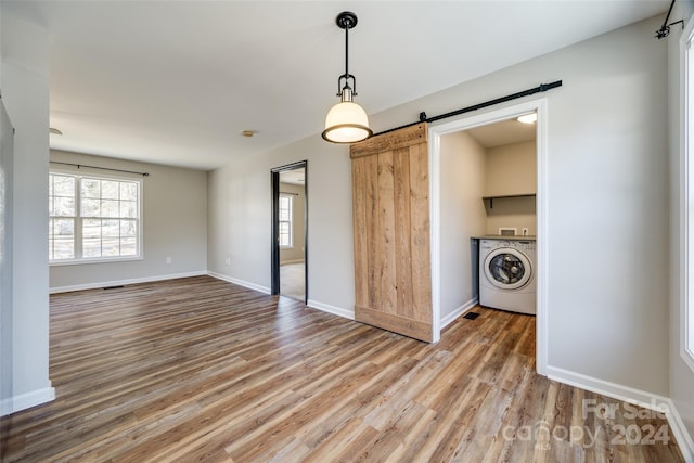 interior space with washer / clothes dryer, hardwood / wood-style floors, and a barn door