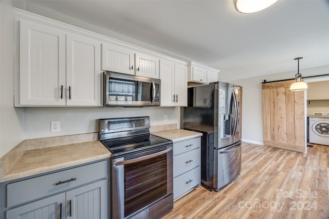 kitchen featuring a barn door, washer / clothes dryer, light hardwood / wood-style floors, white cabinets, and appliances with stainless steel finishes