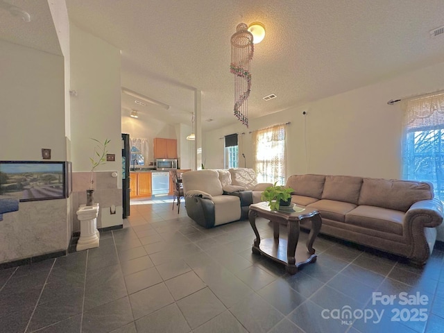 8430 Stoneman Pl, Charlotte, NC 28217 - living room featuring lofted ceiling, dark tile patterned floors, visible vents, and a textured ceiling