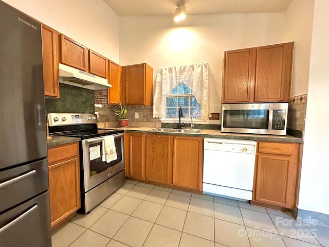 8430 Stoneman Pl, Charlotte, NC 28217 - kitchen with under cabinet range hood, a sink, appliances with stainless steel finishes, tasteful backsplash, and dark countertops
