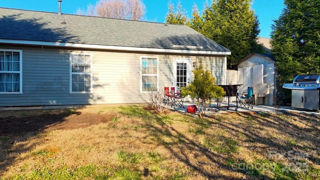 8430 Stoneman Pl, Charlotte, NC 28217 - rear view of property with an outbuilding, a patio, roof with shingles, a lawn, and a storage unit