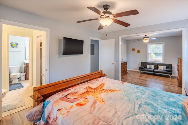 bedroom featuring ceiling fan, light wood-type flooring, and ensuite bath