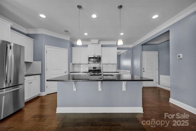 kitchen featuring pendant lighting, white cabinetry, stainless steel appliances, and a center island with sink