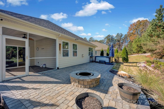 view of patio / terrace with ceiling fan, an outdoor fire pit, and a hot tub