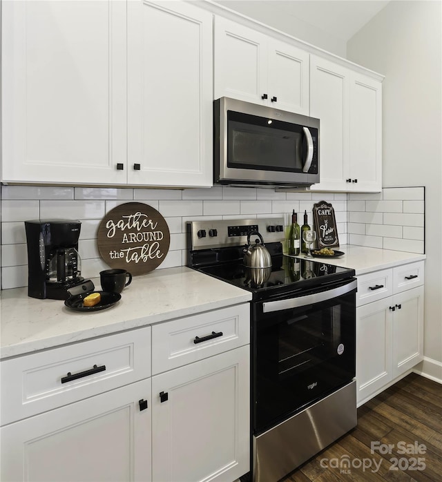 kitchen featuring light stone counters, dark wood-type flooring, tasteful backsplash, white cabinetry, and appliances with stainless steel finishes