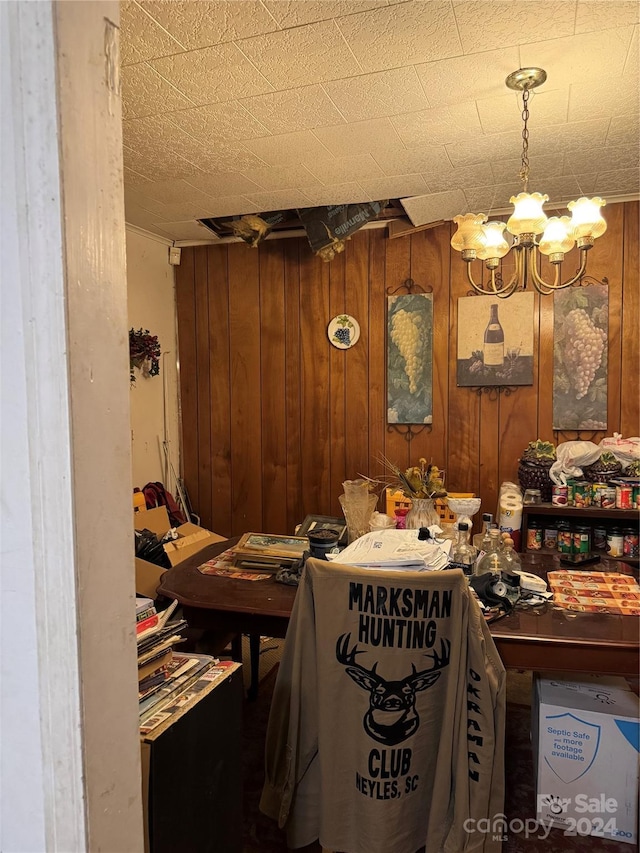 miscellaneous room featuring wood walls and a chandelier