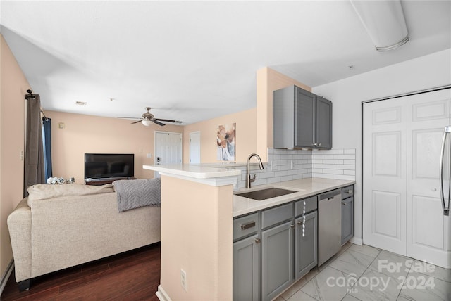 kitchen featuring stainless steel dishwasher, gray cabinetry, kitchen peninsula, and sink