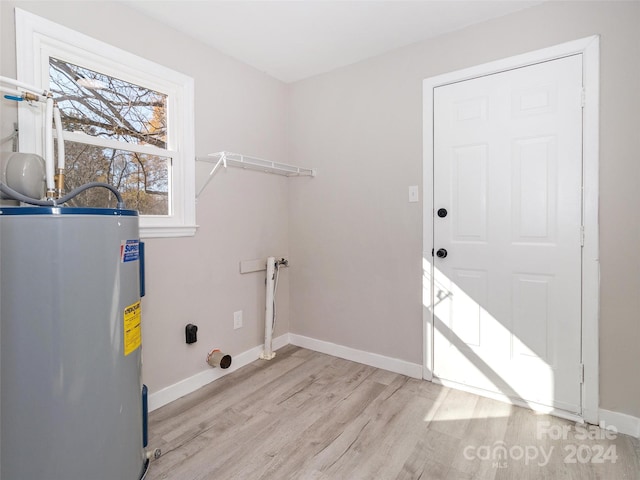 washroom with hookup for an electric dryer, electric water heater, and light hardwood / wood-style flooring