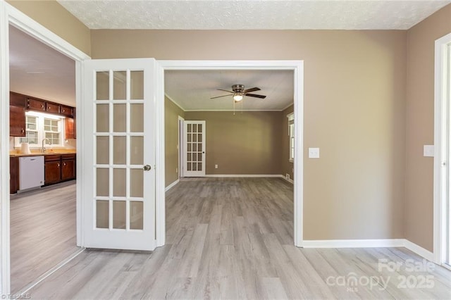 unfurnished room with ceiling fan, french doors, sink, a textured ceiling, and light wood-type flooring