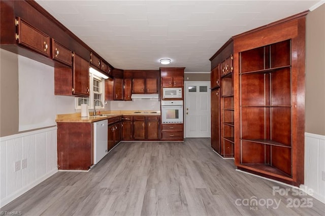 kitchen featuring crown molding, sink, white appliances, and light wood-type flooring