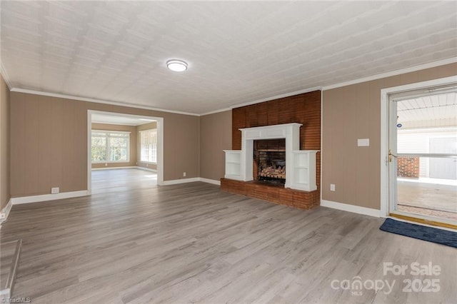 unfurnished living room featuring light wood-type flooring, a brick fireplace, and ornamental molding