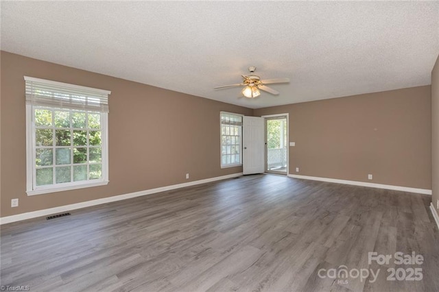 empty room with ceiling fan, wood-type flooring, and a textured ceiling