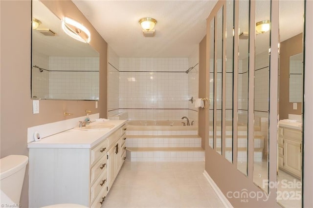 bathroom with toilet, vanity, tiled bath, and tile patterned floors