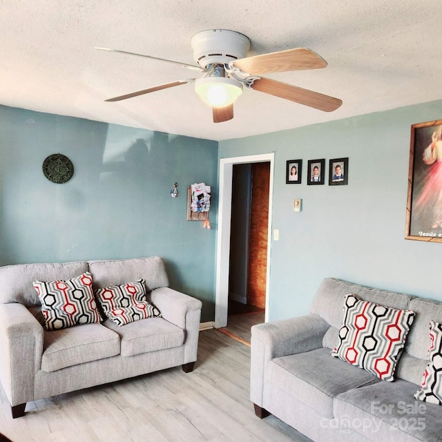 living room with ceiling fan, wood-type flooring, and a textured ceiling