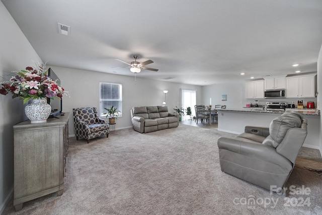 living room with light colored carpet and ceiling fan