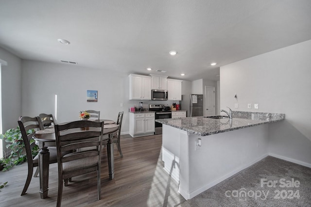 kitchen featuring sink, appliances with stainless steel finishes, dark hardwood / wood-style flooring, light stone counters, and white cabinetry