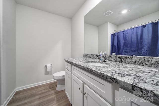 bathroom featuring vanity, hardwood / wood-style flooring, toilet, and curtained shower