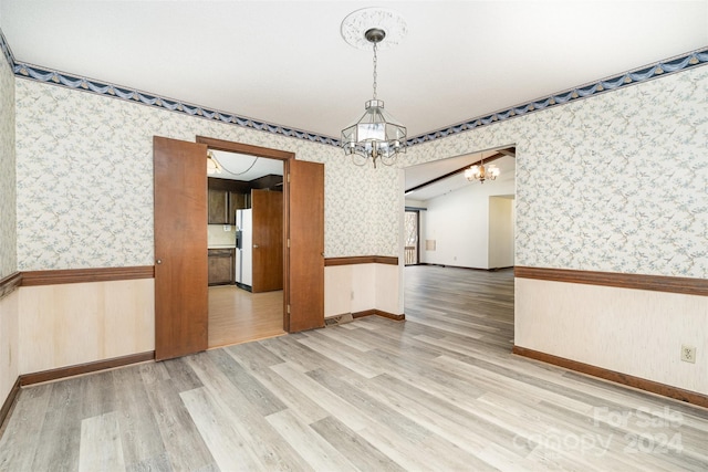 unfurnished dining area featuring hardwood / wood-style floors, a notable chandelier, and lofted ceiling