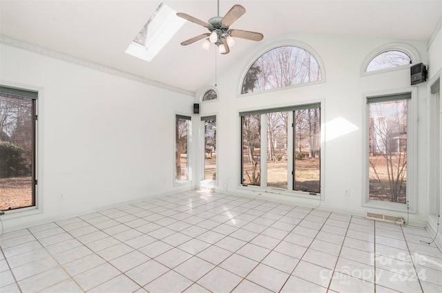 tiled spare room with a skylight, ceiling fan, plenty of natural light, and high vaulted ceiling