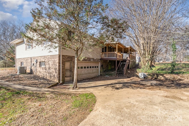 back of property with central AC unit, a garage, and a deck