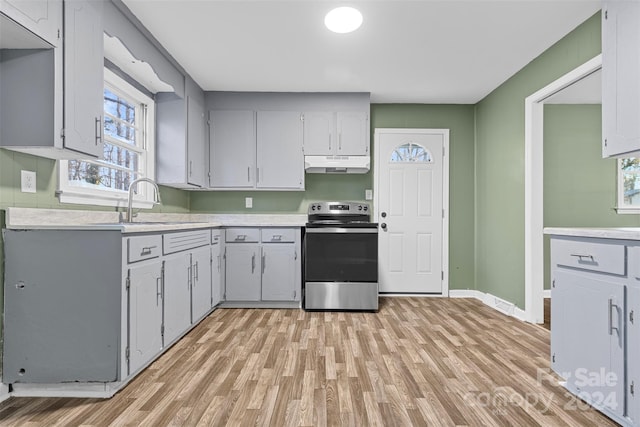 kitchen with gray cabinetry, electric range, sink, and light hardwood / wood-style floors