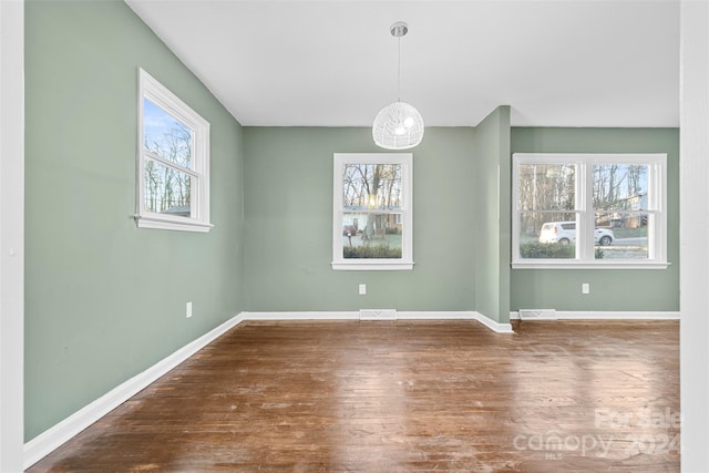 unfurnished dining area featuring dark wood-type flooring and a healthy amount of sunlight