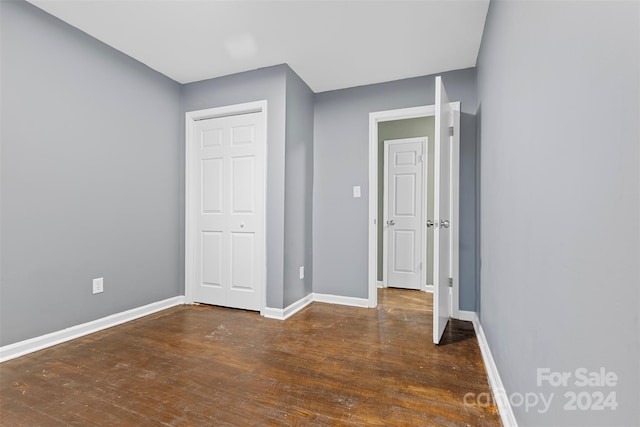 unfurnished bedroom with a closet and dark wood-type flooring