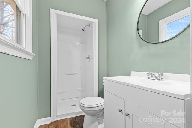 bathroom with a shower, vanity, wood-type flooring, and toilet