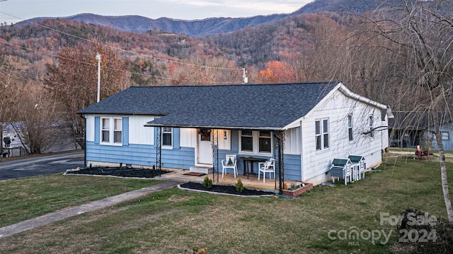 ranch-style house with a mountain view, a front lawn, and a porch