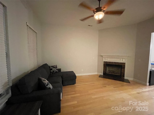 living room featuring ceiling fan, light hardwood / wood-style flooring, and a fireplace