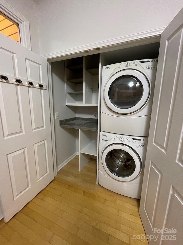 clothes washing area featuring stacked washing maching and dryer and light wood-type flooring