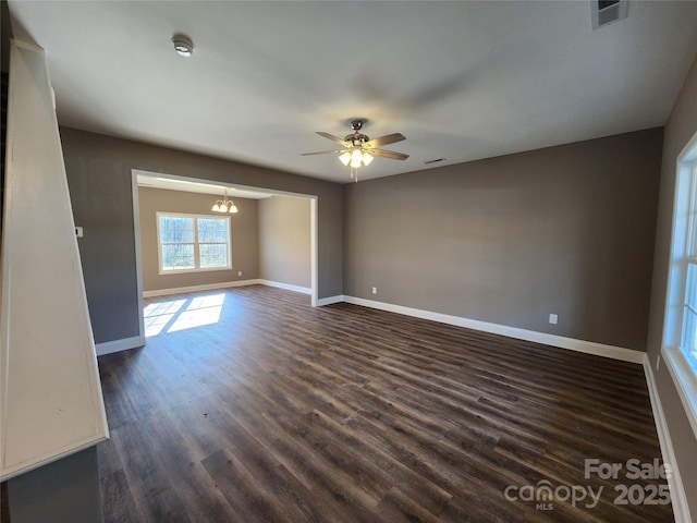 spare room featuring ceiling fan with notable chandelier and dark hardwood / wood-style floors