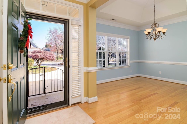 foyer entrance featuring crown molding, hardwood / wood-style floors, and a chandelier