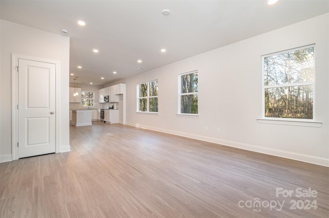 unfurnished living room with light wood-type flooring and a wealth of natural light