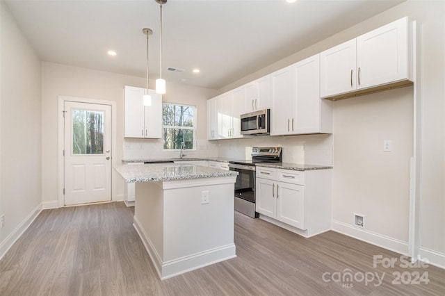 kitchen with white cabinetry, a kitchen island, stainless steel appliances, and decorative light fixtures