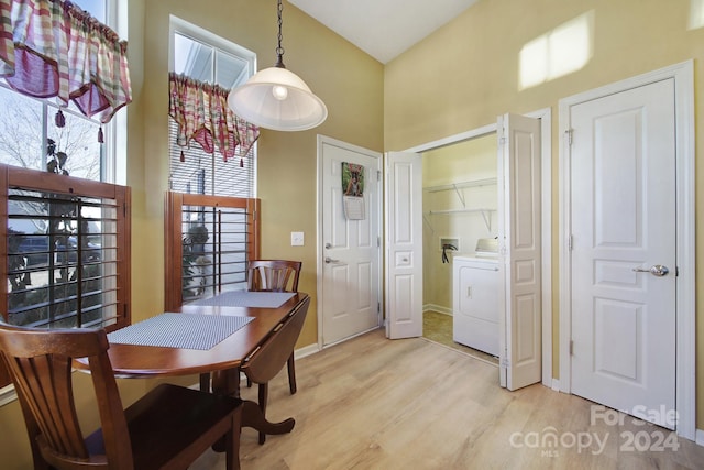 dining area with a towering ceiling, light hardwood / wood-style floors, and washer / dryer