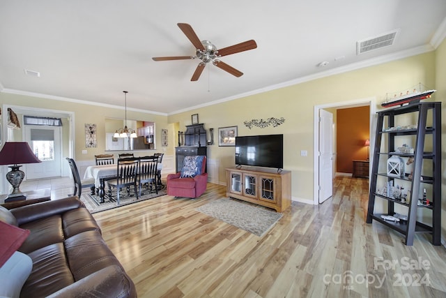 living room with ceiling fan with notable chandelier, hardwood / wood-style flooring, and ornamental molding