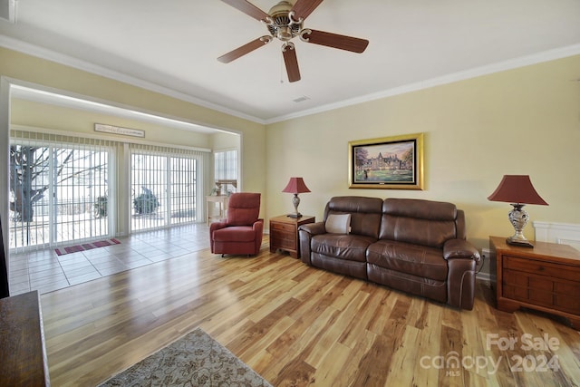 living room featuring ceiling fan, ornamental molding, and light wood-type flooring