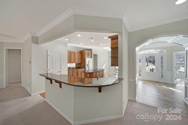 kitchen featuring kitchen peninsula, a breakfast bar, light carpet, and white fridge with ice dispenser