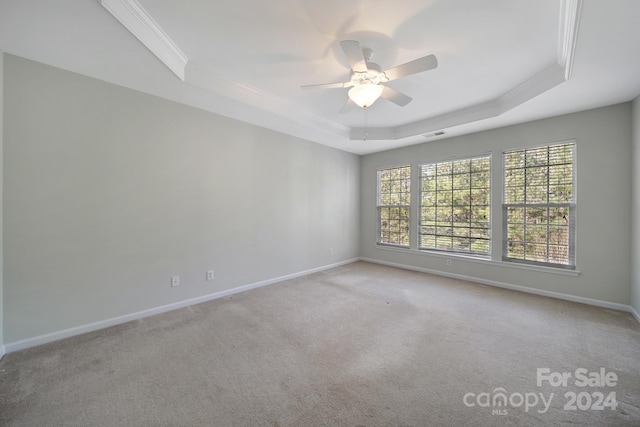 carpeted spare room featuring ceiling fan, a raised ceiling, and crown molding