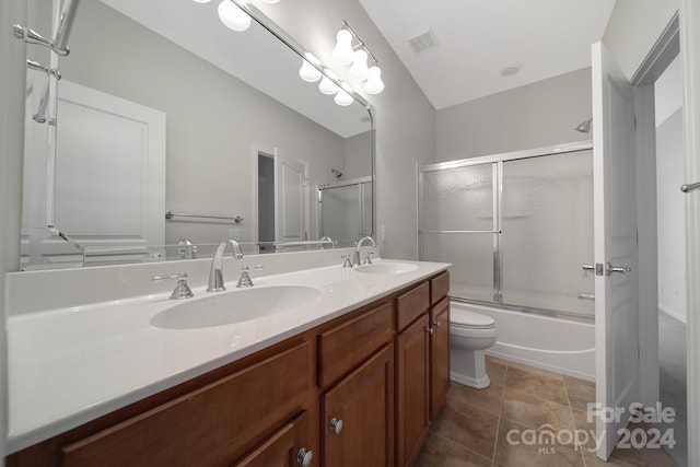 full bathroom with combined bath / shower with glass door, vanity, and toilet